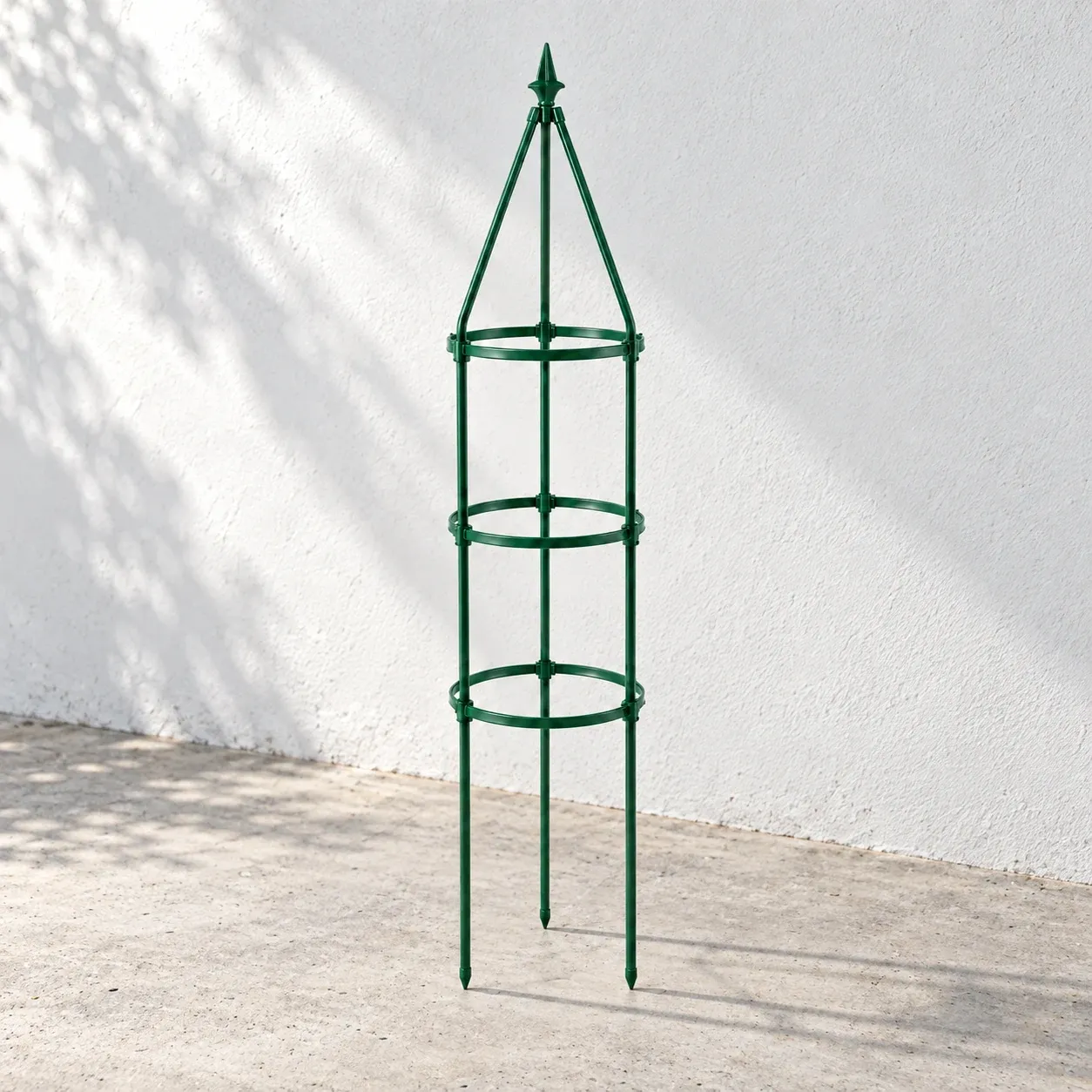 Green three-ring garden trellis on a pale gray terrace