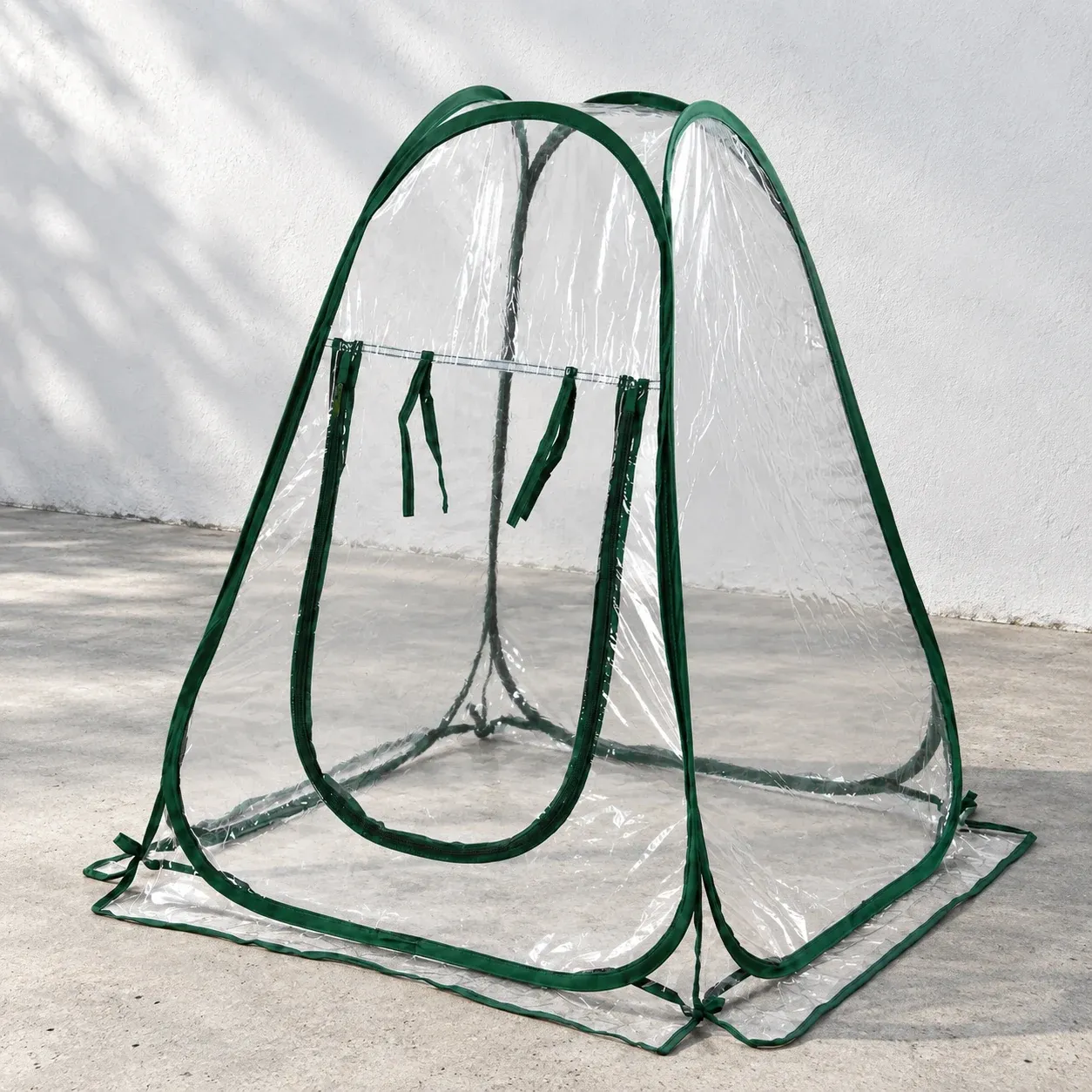 Clear folding plant cover with green edging on a gray terrace